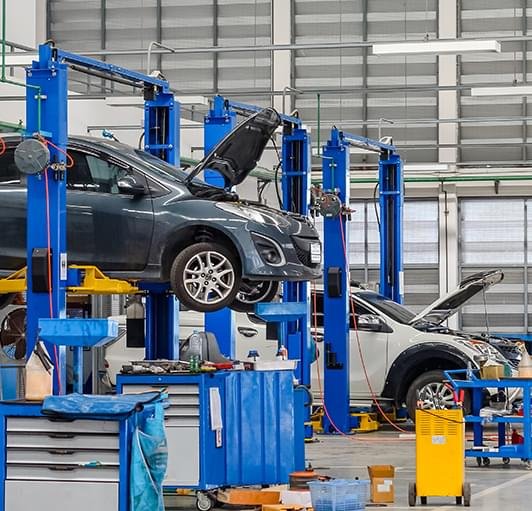 Cars being serviced on hydraulic lifts at a multi-brand garage